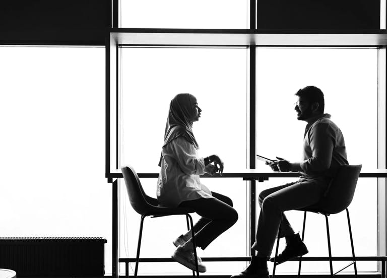 A man and a women sitting at a tall table discussing the difference between reskilling and upskilling.