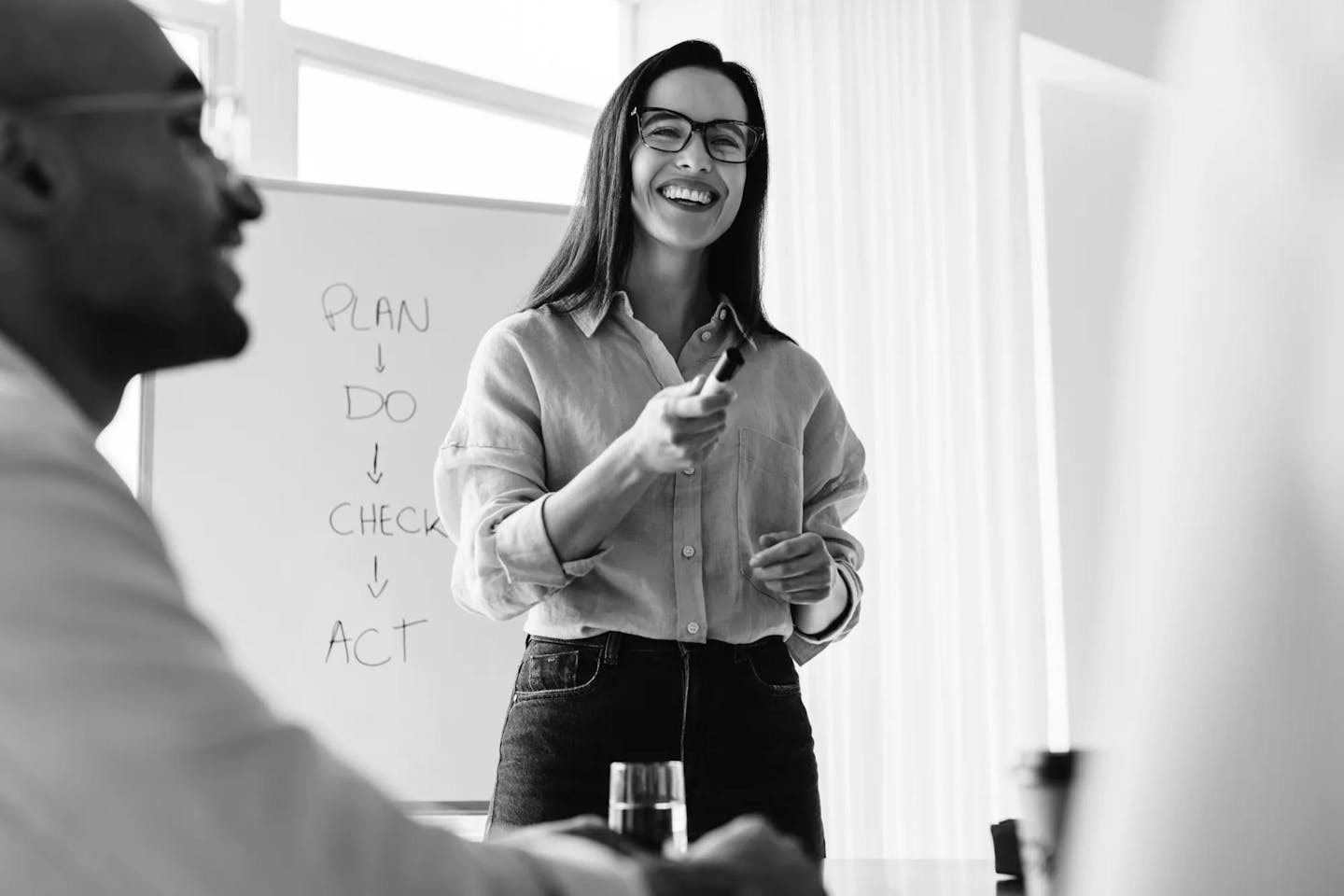 A woman standing in front of a whiteboard holding a marker as the group discusses hiring tech talent.